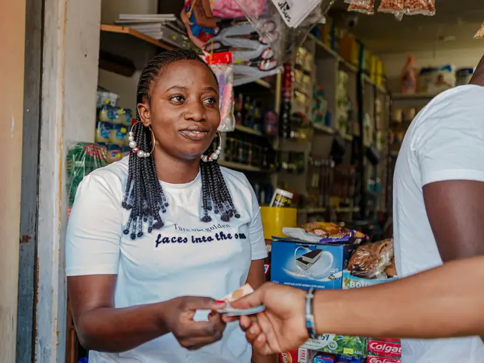 A shopkeeper taking cash from a customer at the door of her shop